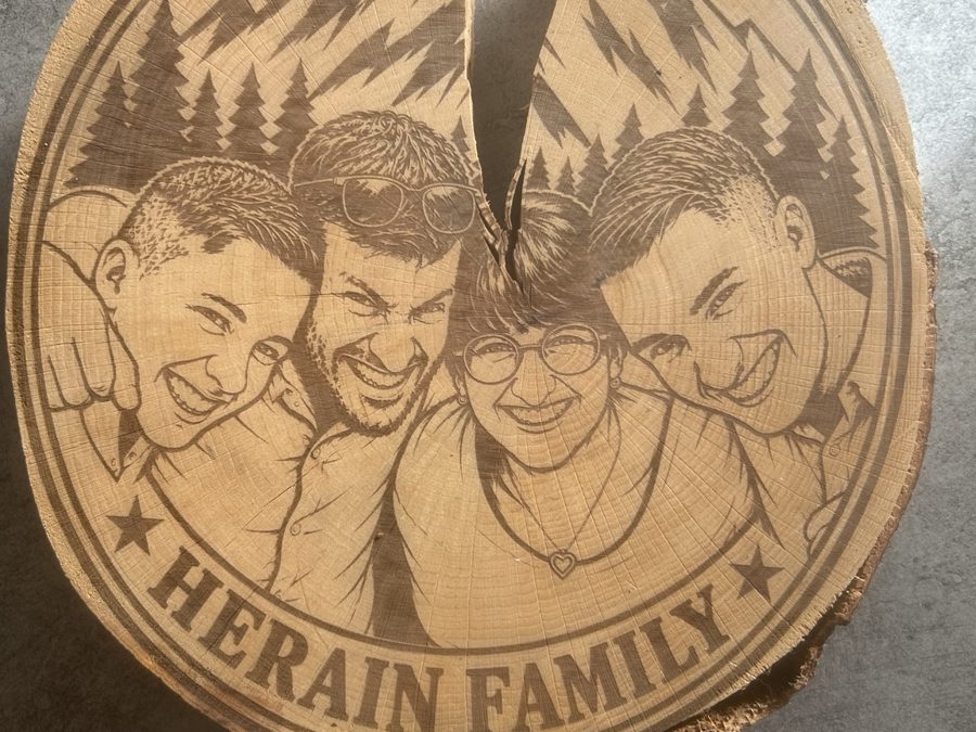 Dessous de plat en rondelle de bûche gravé d'un portrait de famille sur fond de montagnes, avec l'inscription Herain Family